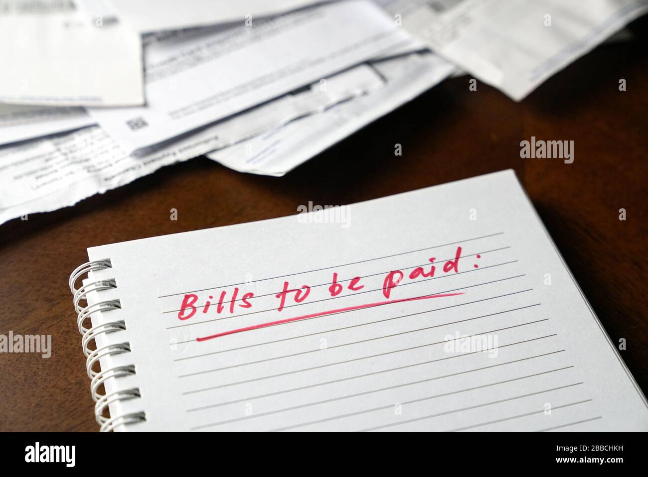 Fatture da pagare, scritte in rosso sul notebook con fatture e fatture in background. Concetto di disoccupazione o recessione. Foto Stock