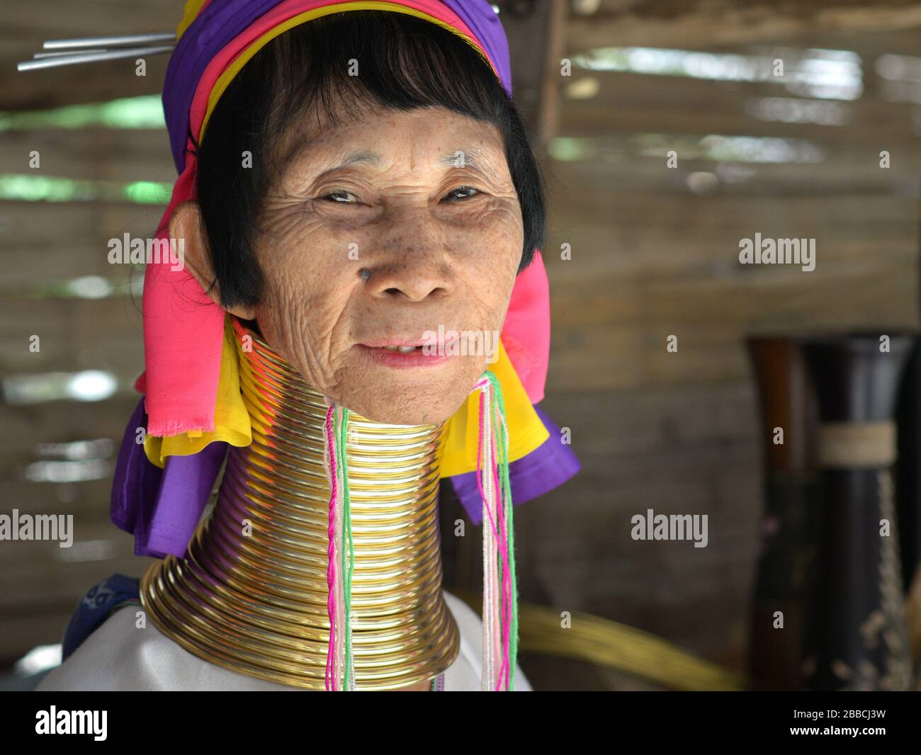 Vecchia donna di Kayan tailandese/birmano a collo lungo (la 'giraffe woman') con lucidato tribale Padaung in ottone anelli / bobine pone per la macchina fotografica. Foto Stock