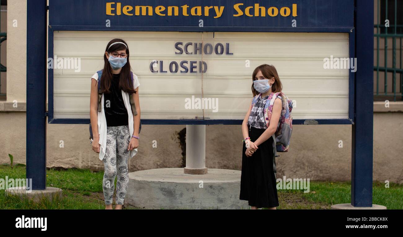 Una ragazza è preoccupata che la sua scuola sia chiusa. Lei è desiderosa di assistere con una maschera di faccia sopra. Foto Stock