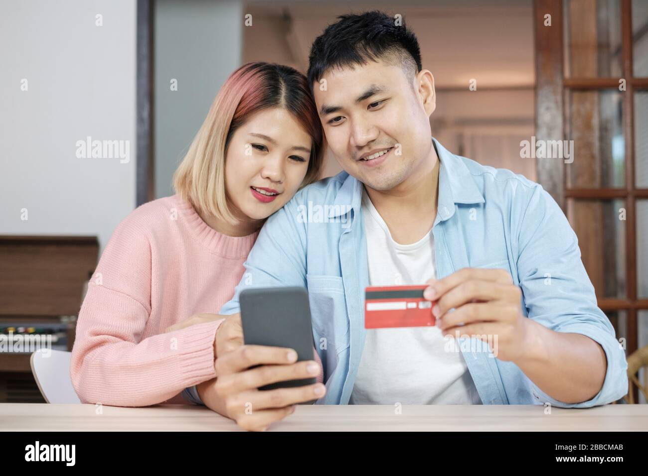 Asian giovane utilizzare telefoni cellulari shopping online con carta di credito insieme nel salotto di casa.matura nel concetto di casa Foto Stock