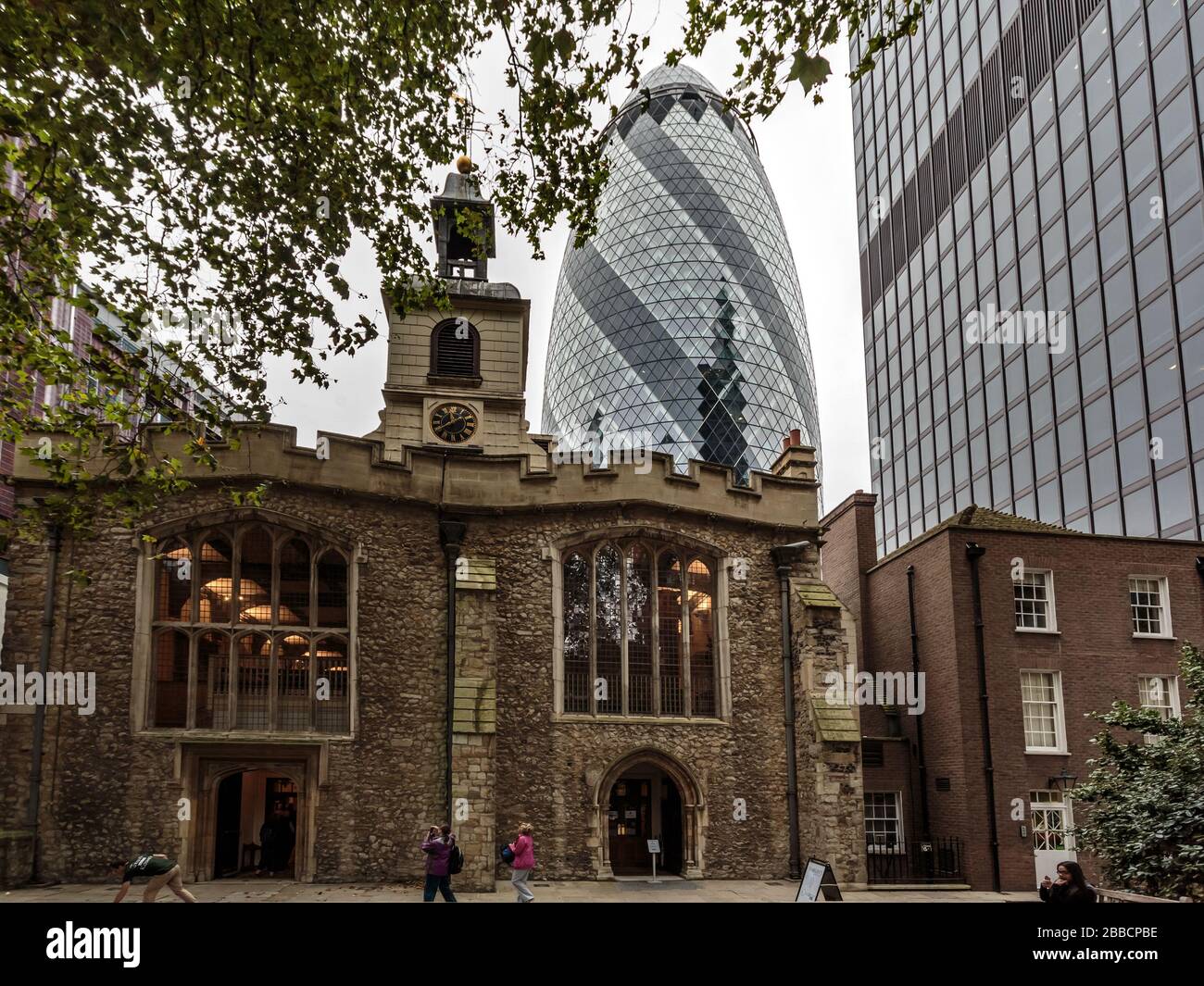 Vecchio incontra nuovo - facciata della chiesa di St Helen Bishopsgate con il grattacielo Gherkin sullo sfondo, Londra, Inghilterra Foto Stock