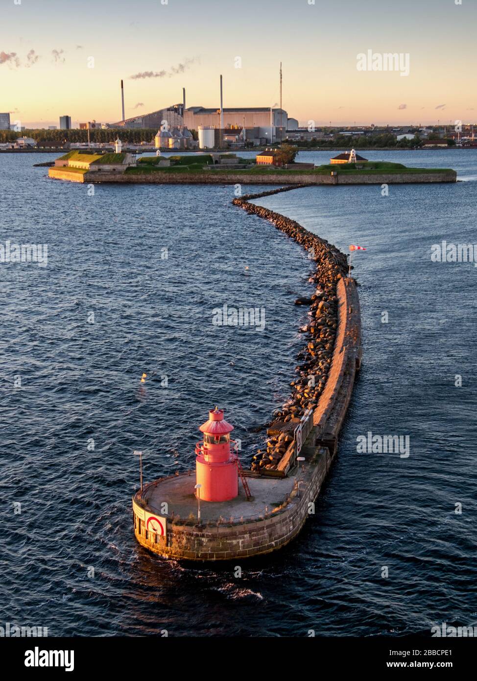 Un faro rosso sulla scogliera di pietra all'ingresso del porto per il trasporto commerciale a Copenhagen, Danimarca Foto Stock