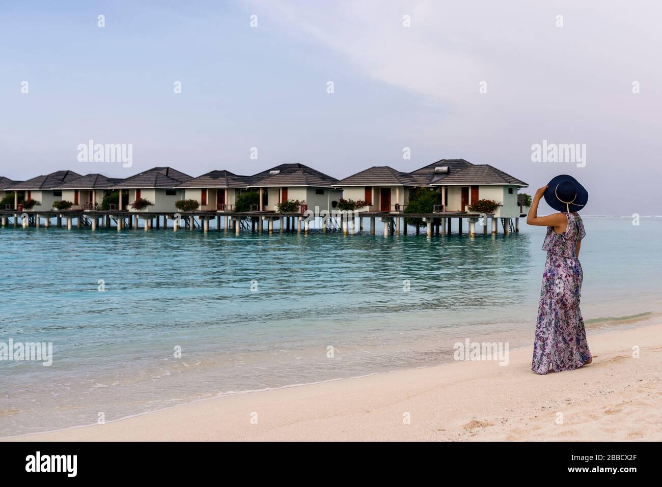 Donna attraente in spiaggia e relax godendo in vacanza. La vacanza estiva concetto. Il mare azzurro e la sabbia bianca. Moda ragazza godendo sulla riva del mare. Foto Stock