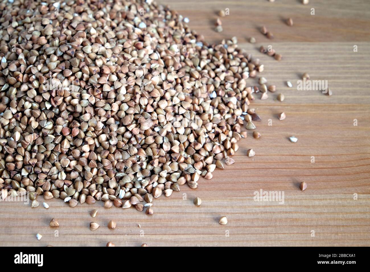 Mucchio di molti grani di grano saraceno sulla superficie del tavolo in legno interno vista frontale primo piano Foto Stock