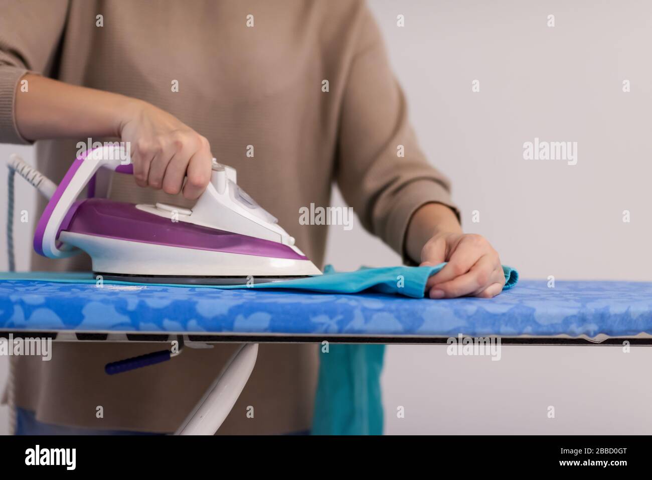 bella casalinga dai capelli rossi, di buon umore, con abiti da stiro  sull'asse da stiro davanti a una parete bianca a casa Foto stock - Alamy