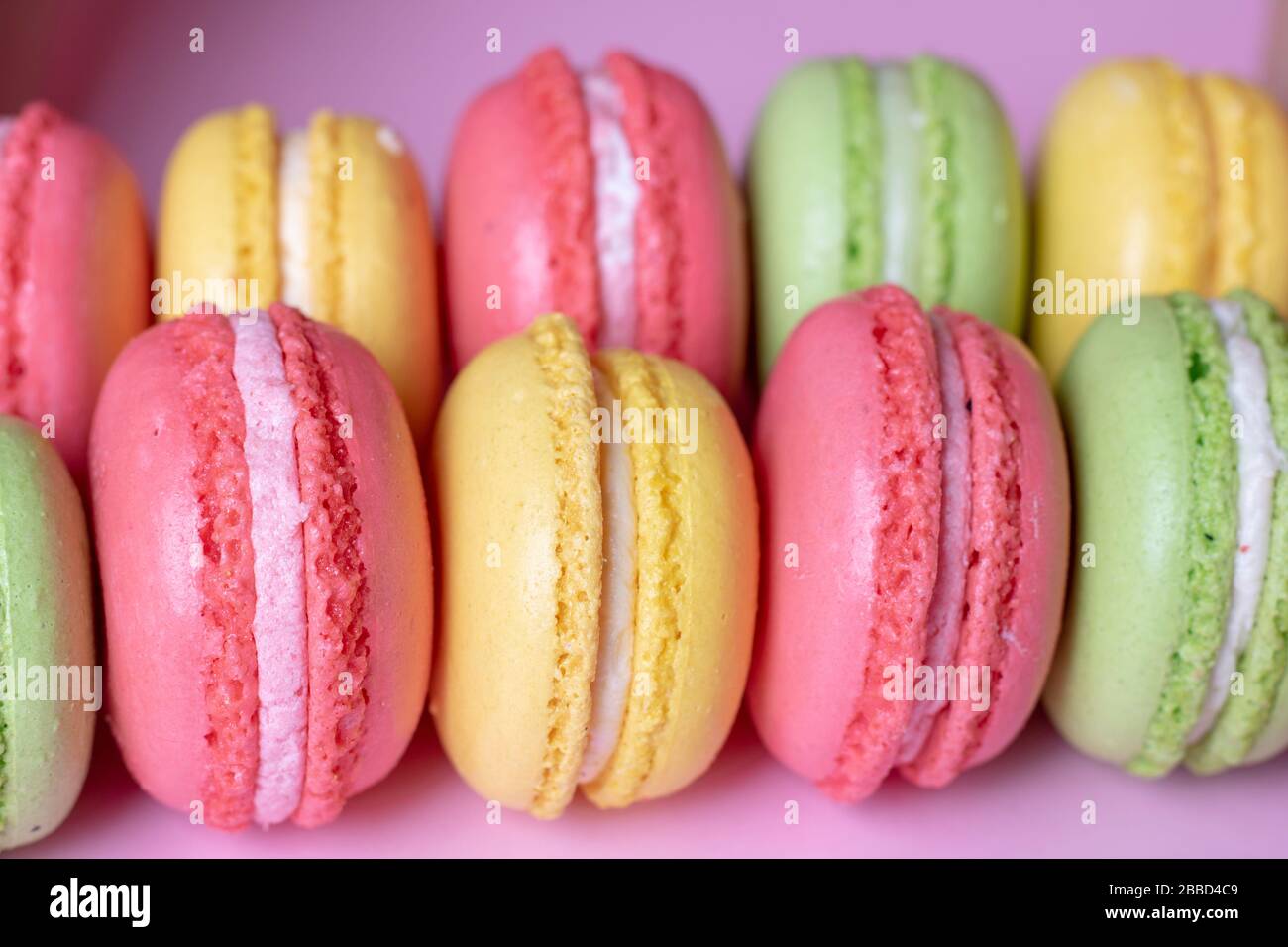 Fila di macaron rossi, gialli e verdi, primo piano Foto Stock