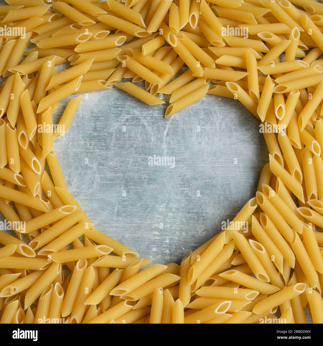 Food background - pasta a penne a secco con forma di cuore per testo, integrale grano crudo ingrediente Foto Stock