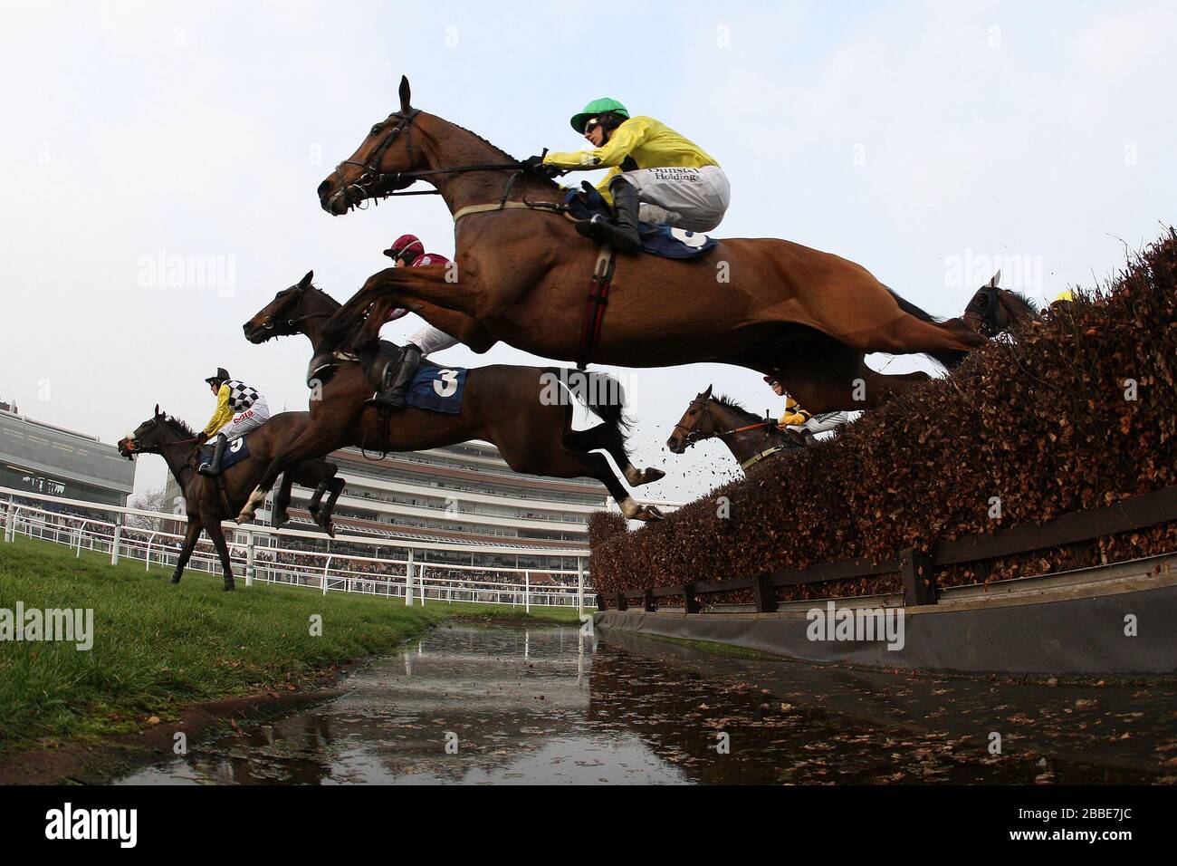 Corridori e corridori prendono il salto d'acqua durante il ponticello di rickety inseguimento dell'handicap del ponticello (in aiuto di West Berkshire Mencap) - corsa del cavallo all'ippodromo di Newbury Foto Stock