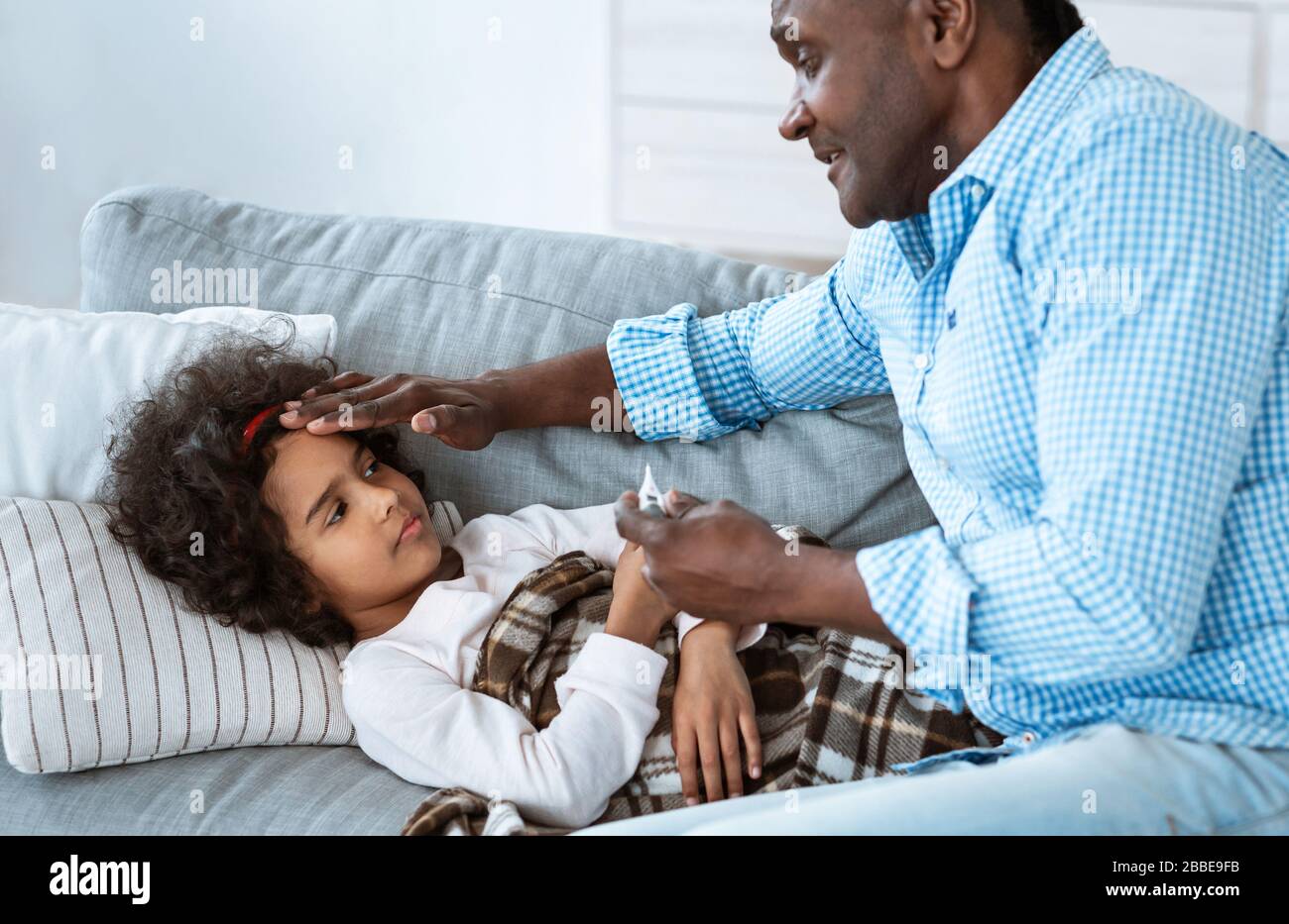 Malattia infettiva. Cute ragazza afroamericana che soffre di febbre e nonno di cura accanto a lei Foto Stock