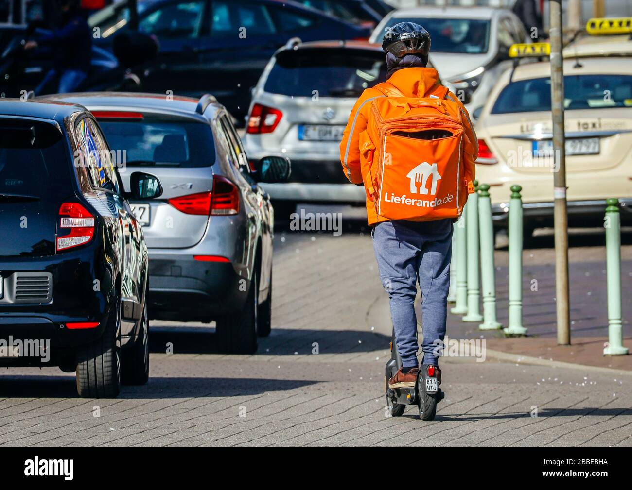 Essen, Ruhr Area, Renania Settentrionale-Vestfalia, Germania - Servizio di consegna Lieferando, un autista di corriere sulla strada con uno scooter elettrico consegna l'ordigno Foto Stock
