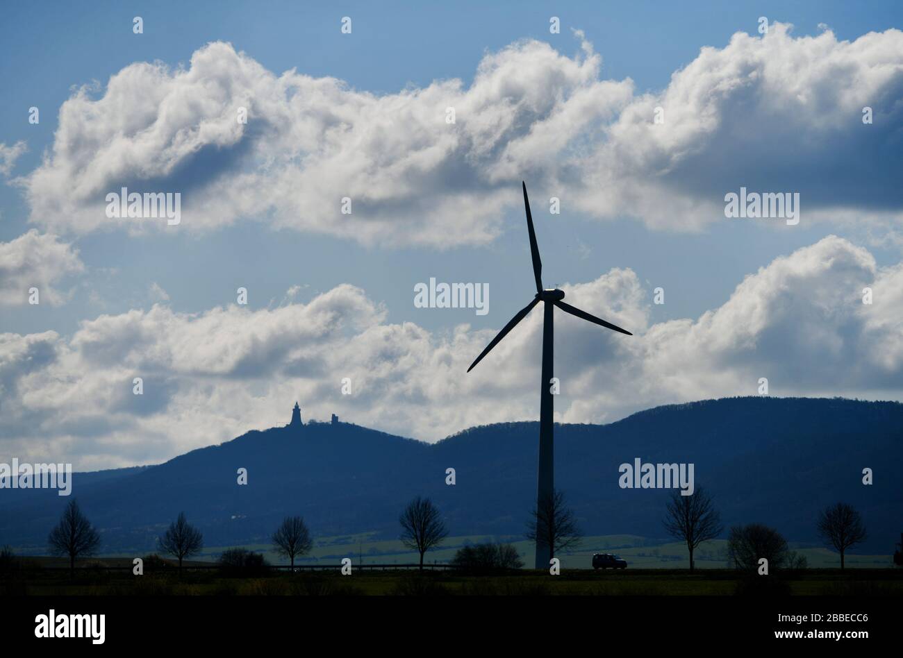 Bad Frankenhausen, Germania. 31st Mar, 2020. Un'auto conduce accanto a un mulino a vento di fronte al monumento Kyffhäuser su una strada di campagna. Il tempo è previsto per rimanere soleggiato nei prossimi giorni. Merito: Frank May/dpa/Alamy Live News Foto Stock