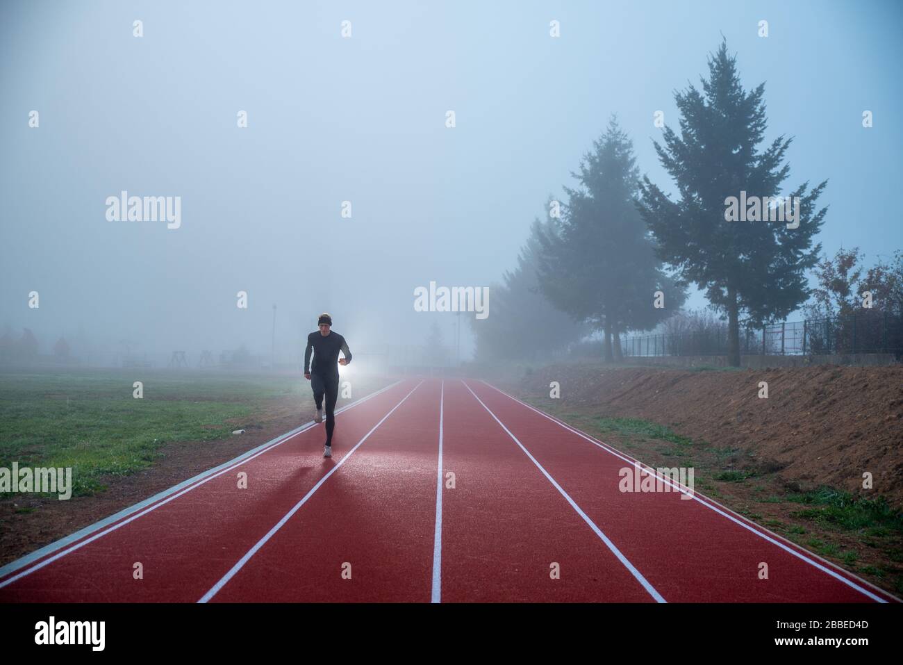 Atleta in pista con linee rosse sopra il cielo blu nebbia. Foto sportiva, spazio di editing Foto Stock