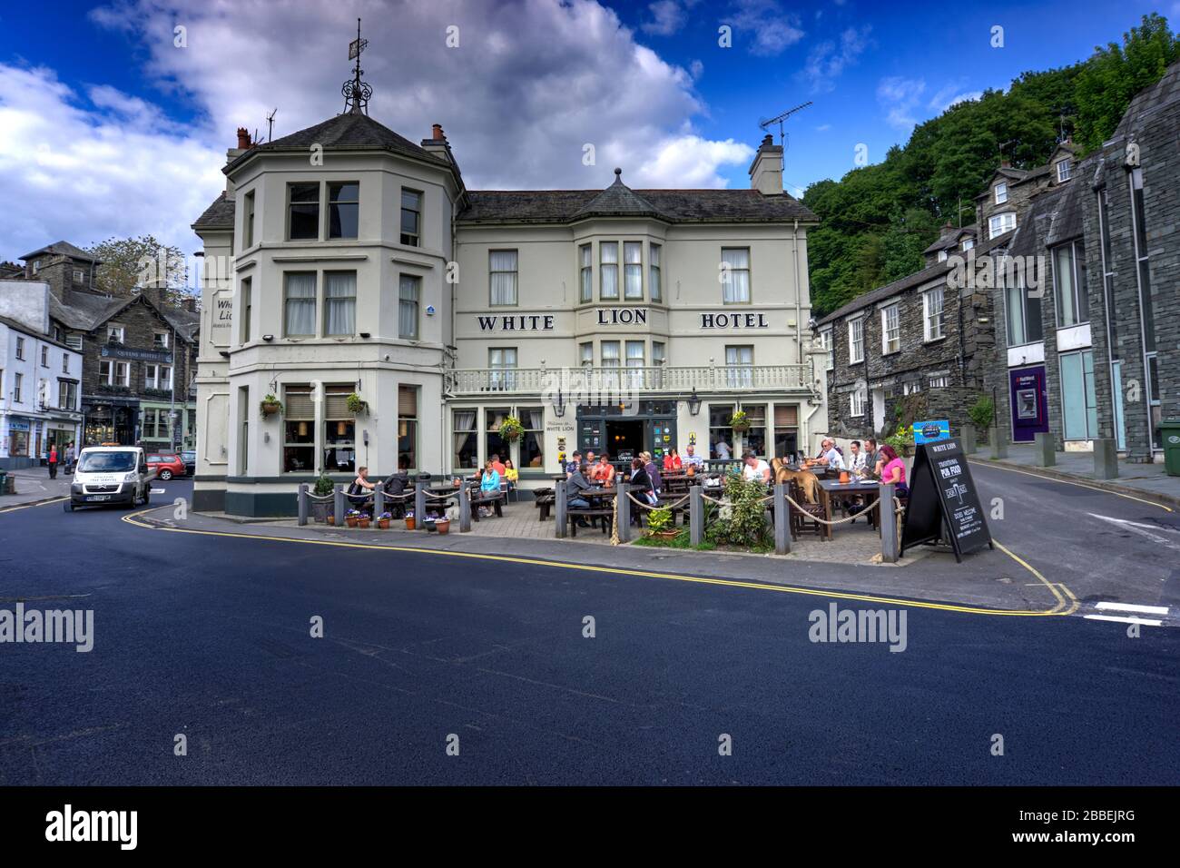 Ambleside, Cumbria, Regno Unito - 16 maggio 2019: White Lion Hotel e la casa pubblica con molti clienti seduti al di fuori di qualche movimento sfocato. Foto Stock