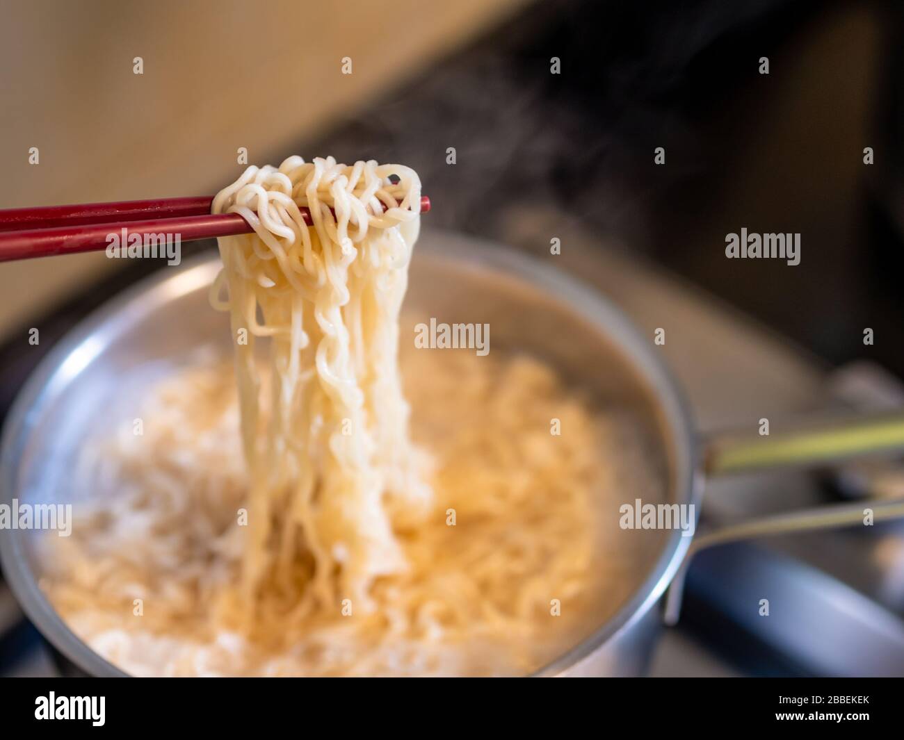 Primo piano di noodles istantanei su bastoni mentre cucinano sopra una stufa della cucina con spazio della copia Foto Stock