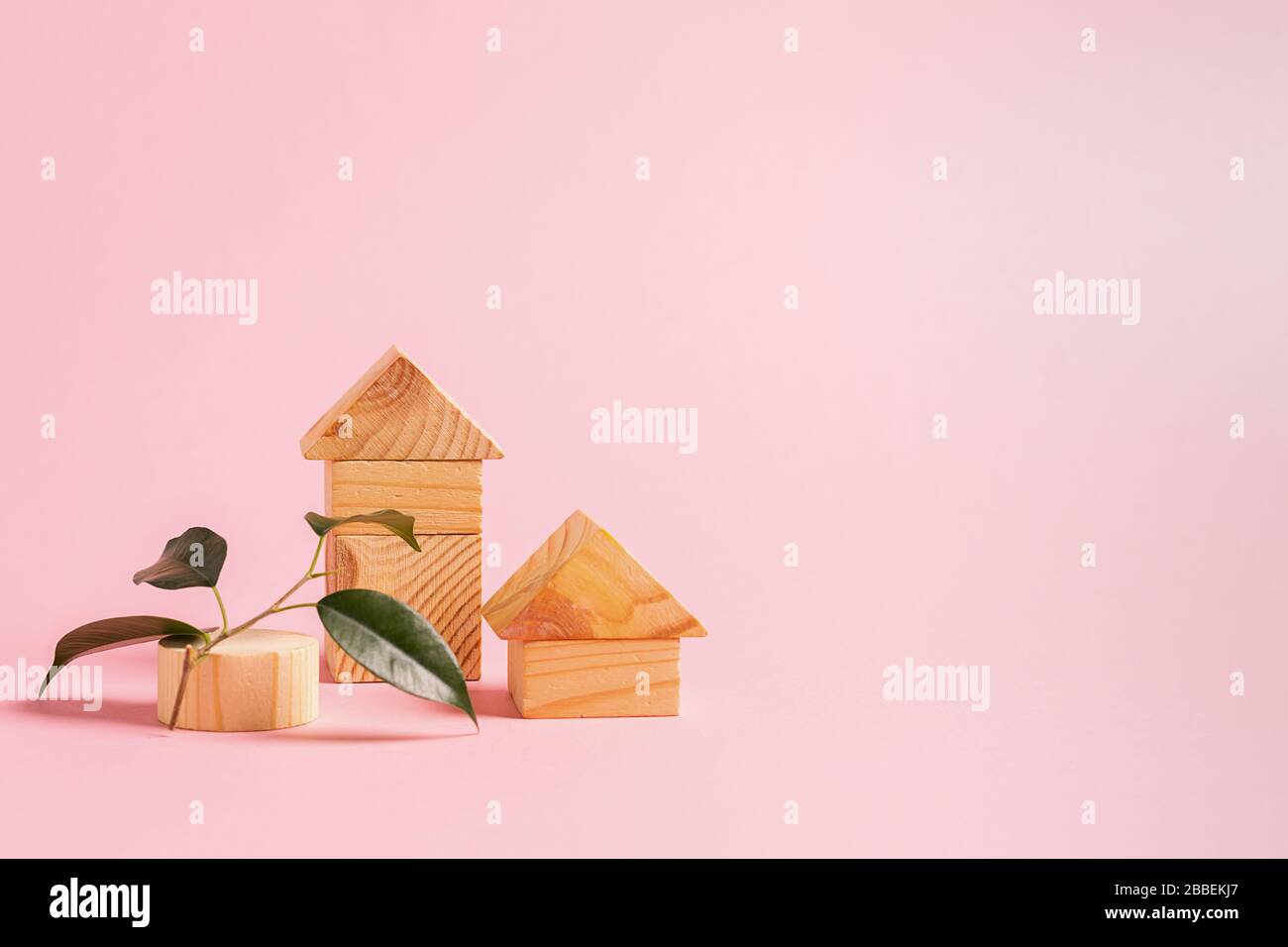 Case grandi e piccole di cubetti di legno su sfondo rosa. Il concetto di costruzione di case a partire dal rispetto dell'ambiente Foto Stock