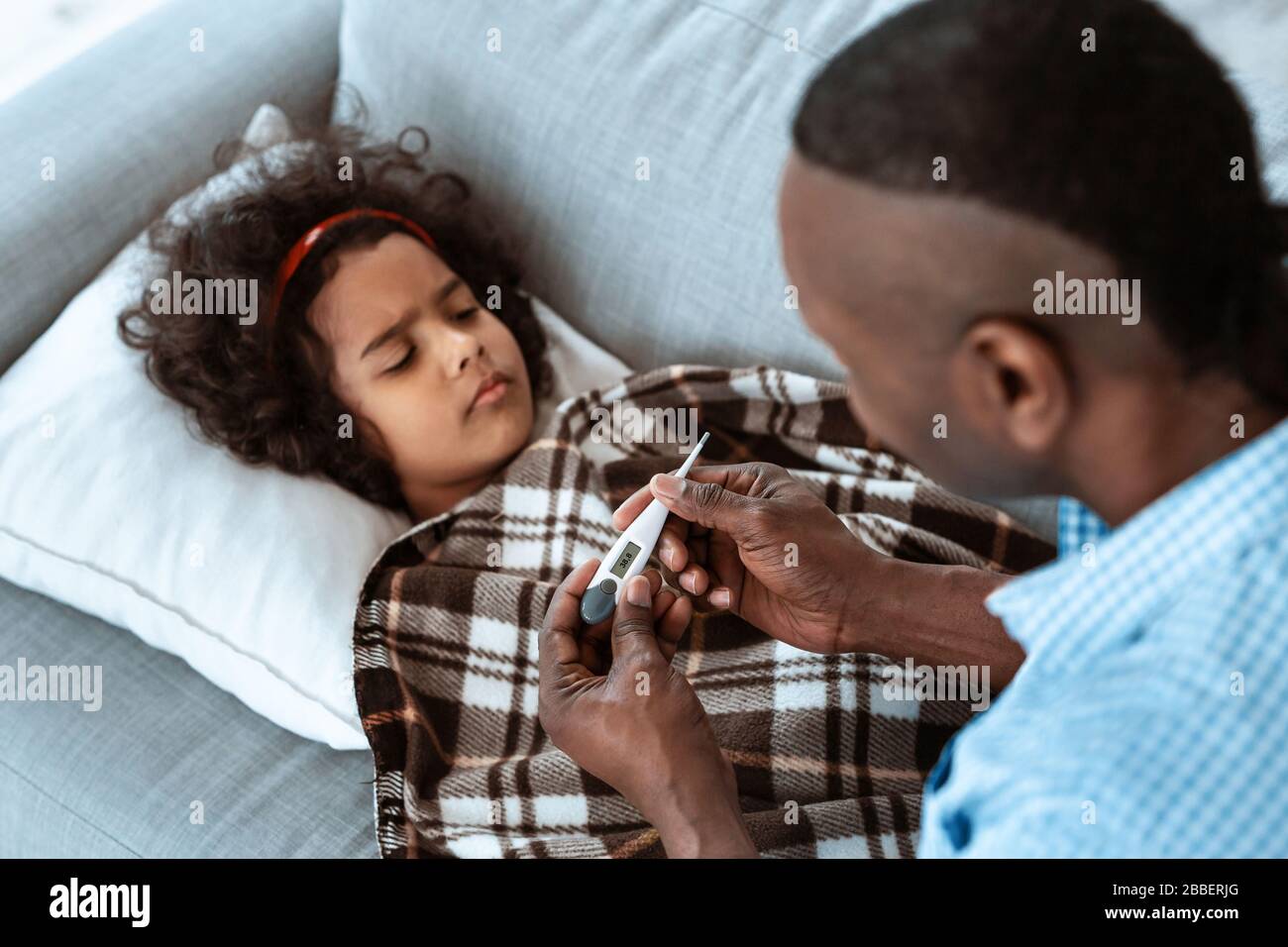 Epidemia di coronavirus. Amante nonno con termometro prendersi cura della sua nipote ammalata a casa Foto Stock