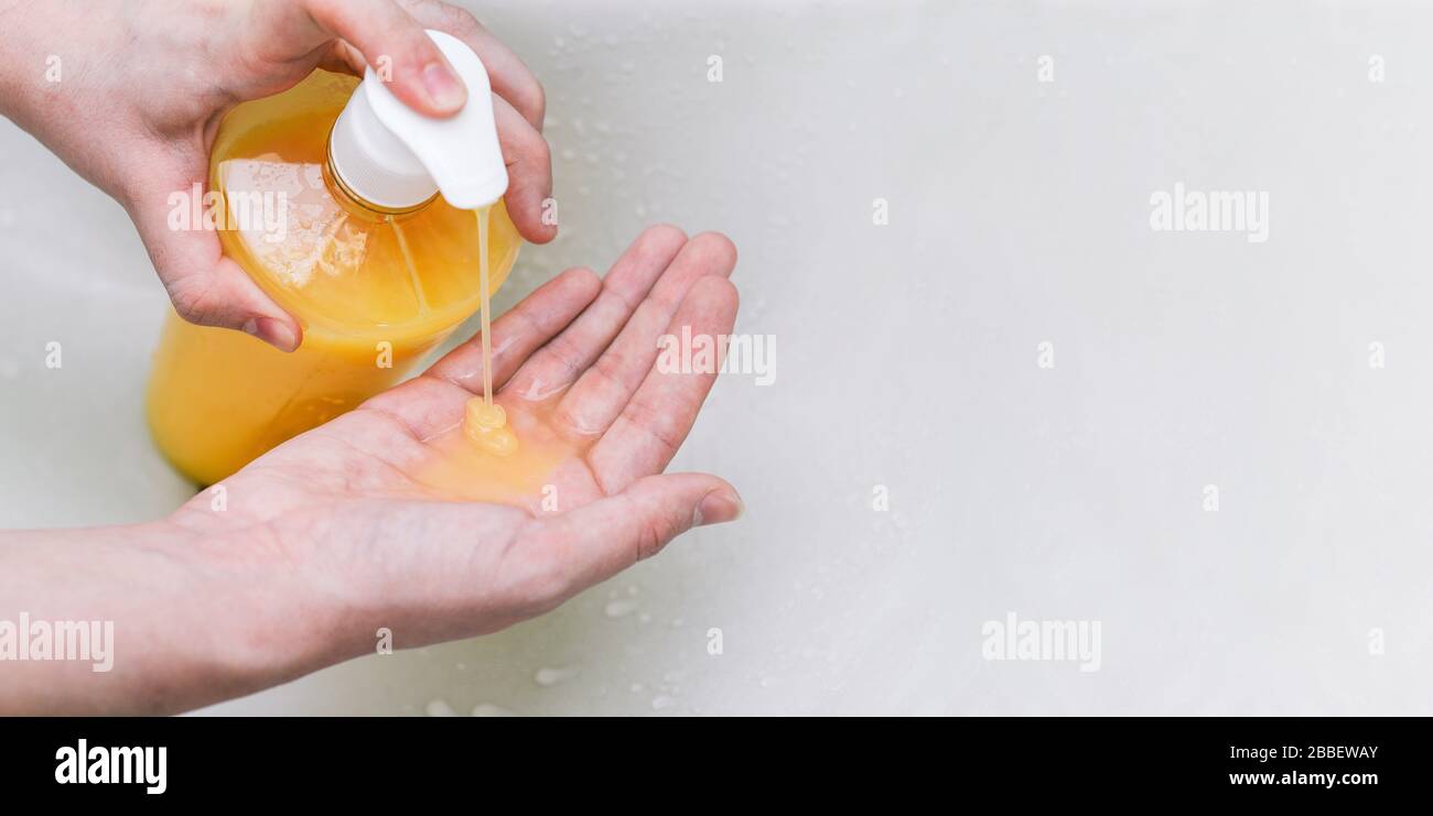 Lavaggio a mano con sapone. Una ragazza stringe un disinfettante antibatterico nelle sue mani da una bottiglia di plastica. Pulizia delle mani da germi, sporcizia e corona Foto Stock