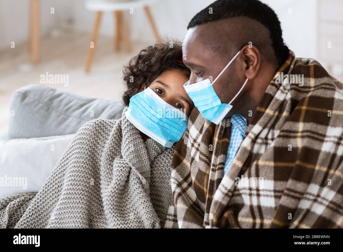 Epidemia mondiale. L'uomo maturo con la sua nipote che indossa le maschere mediche a casa Foto Stock