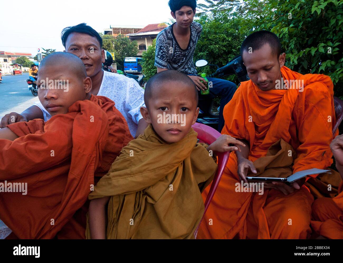 Kambot, Cambogia, Asia: Alcuni giovani studenti buddisti siedono in gruppo mentre giocano con un tablet Foto Stock