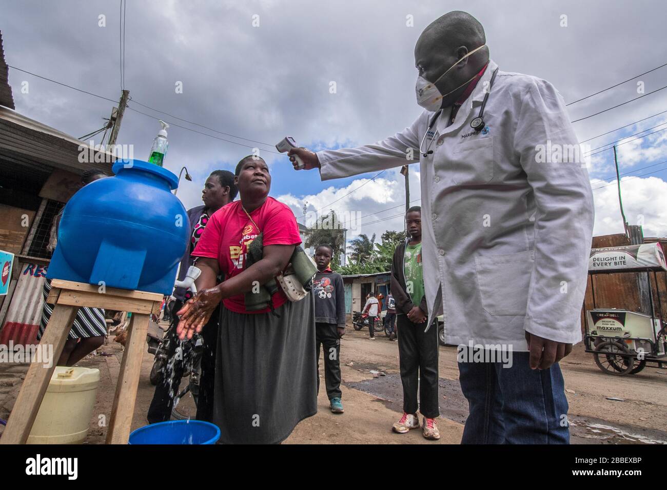 Un medico, Dr Fredrick Ochenge misura la temperatura di una donna in una stazione locale pubblica di lavaggio a mano come misura precauzionale contro la diffusione di Coronavirus in Kibera slums.Kenya Coronavirus casi aumentare a 38 come 7 nuove infezioni sono confermate. Foto Stock