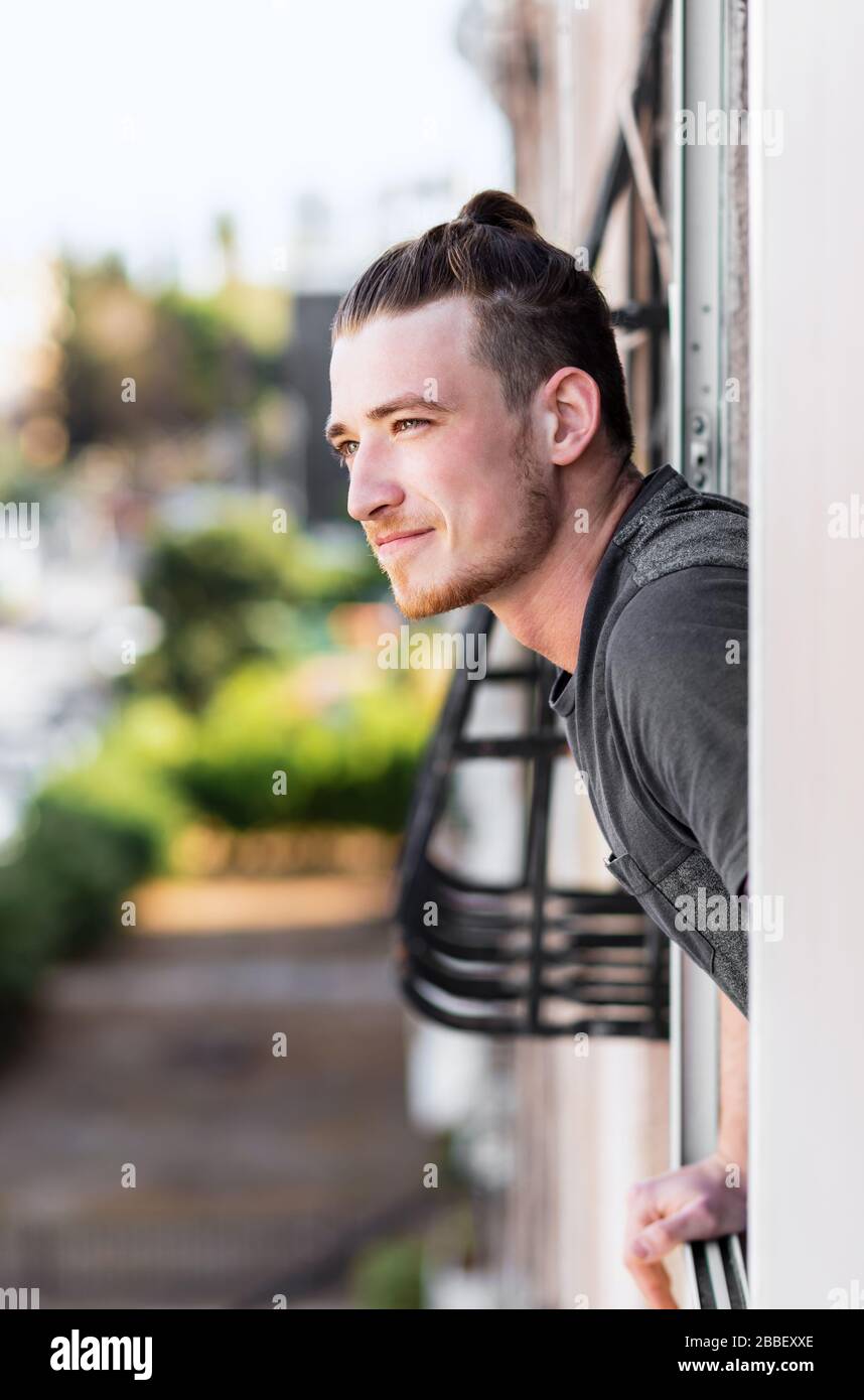 Il giovane scopré la fine della quarantena, si appoggiò fuori dalla finestra e respira profondamente, in un clima gioioso. Il vaccino contro il coronavirus è pronto Foto Stock
