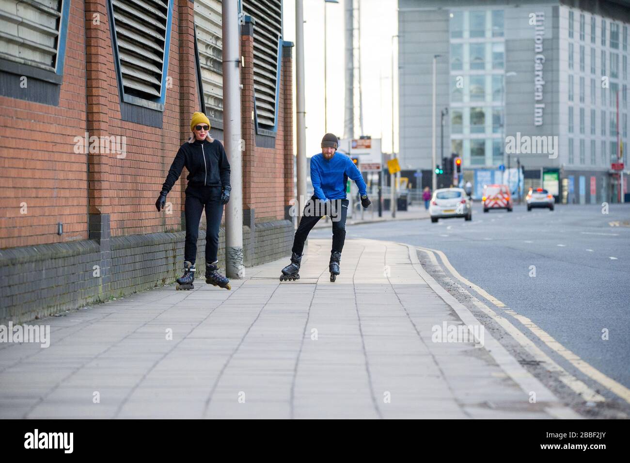 Glasgow, Regno Unito. 30 marzo 2020. Nella foto: Una coppia ha visto il pattinaggio in linea durante il loro regime di esercizio una volta al giorno durante il Coronavirus Lockdown a Glasgow. Dato che le strade sono ora molto tranquille, questo dà luogo a condizioni ideali per pattinare, come tutti i marciapiedi e le superfici si trovano vuote. Credito: Colin Fisher/Alamy Live News. Foto Stock