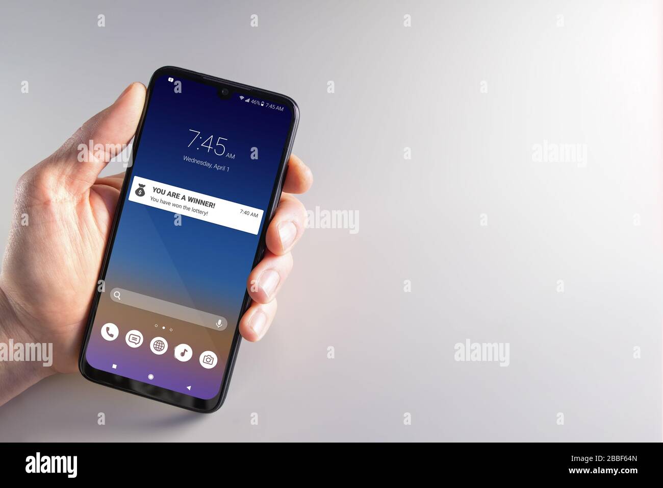 Mano maschile che tiene uno smartphone con notifica del vincitore della lotteria il mese di aprile 1st. Truffa, sciocchi di aprile, criminalità informatica, privacy e concetti tecnologici. Foto Stock