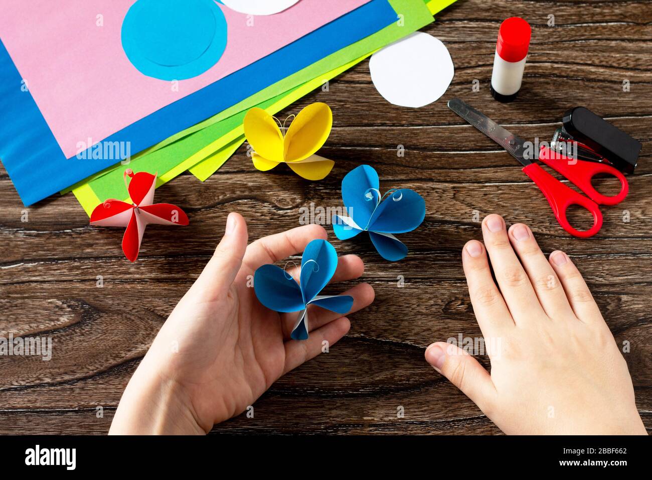 Il bambino può contenere un decoro a farfalla di carta o un garland estivo. Idee di carta fatte a mano. Il progetto della creatività dei bambini, dell'artigianato, dell'artigianato per i bambini. Foto Stock