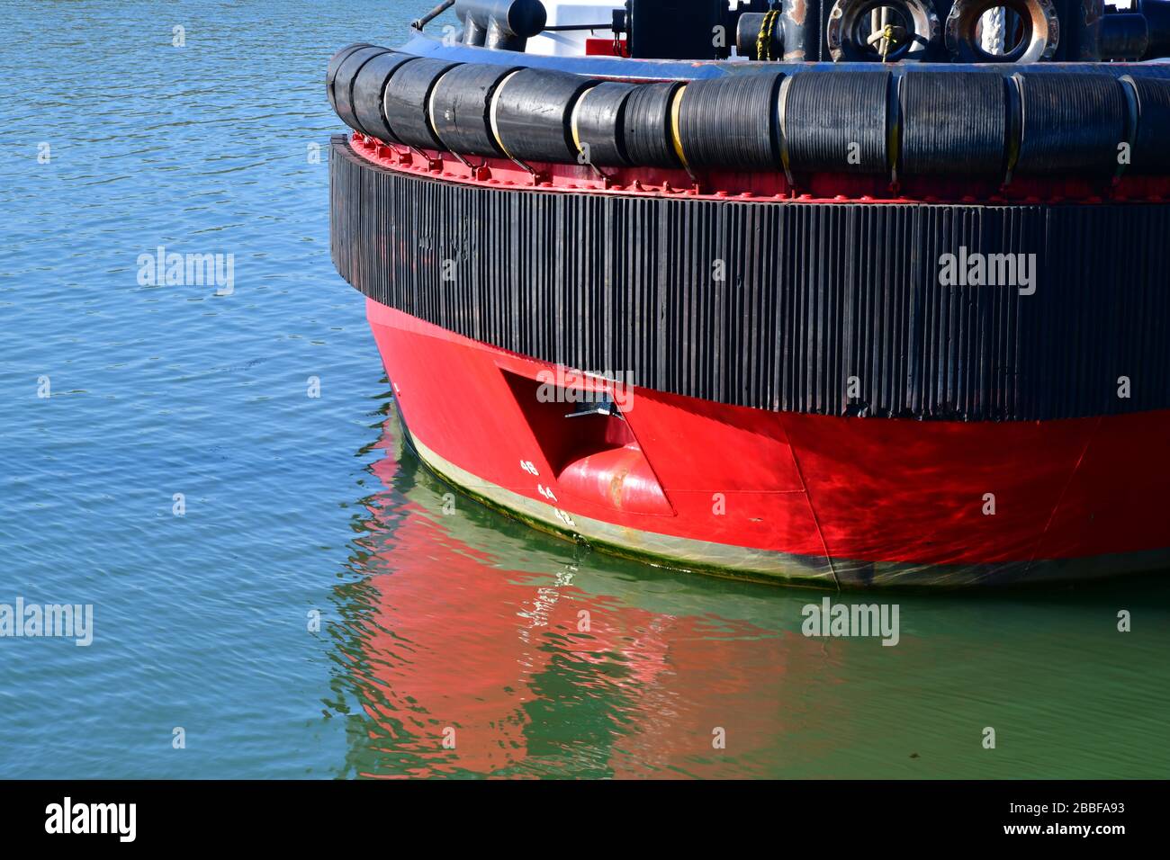 Vista ravvicinata di una sezione dell'arco di una grande barca a rimorchiatore rosso a Rotterdam Europoort. Visualizzazione di ampi parafanghi in gomma per imbarcazioni per la protezione Foto Stock
