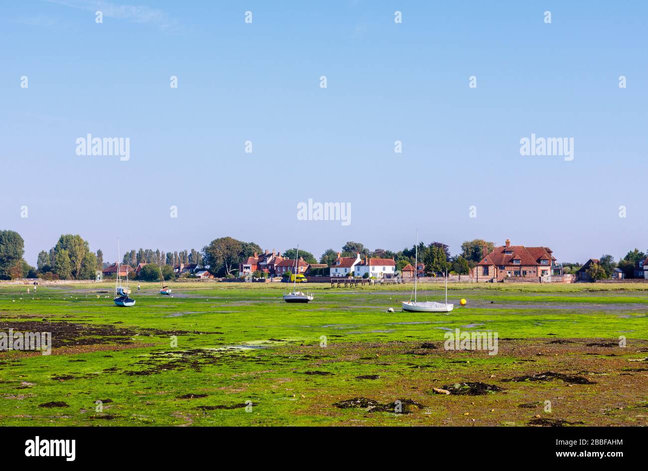 Piccole barche a vela con base a Chichester Harbour su appartamenti di fango con bassa marea a Bosham, un piccolo villaggio costa sud dell'Inghilterra Foto Stock