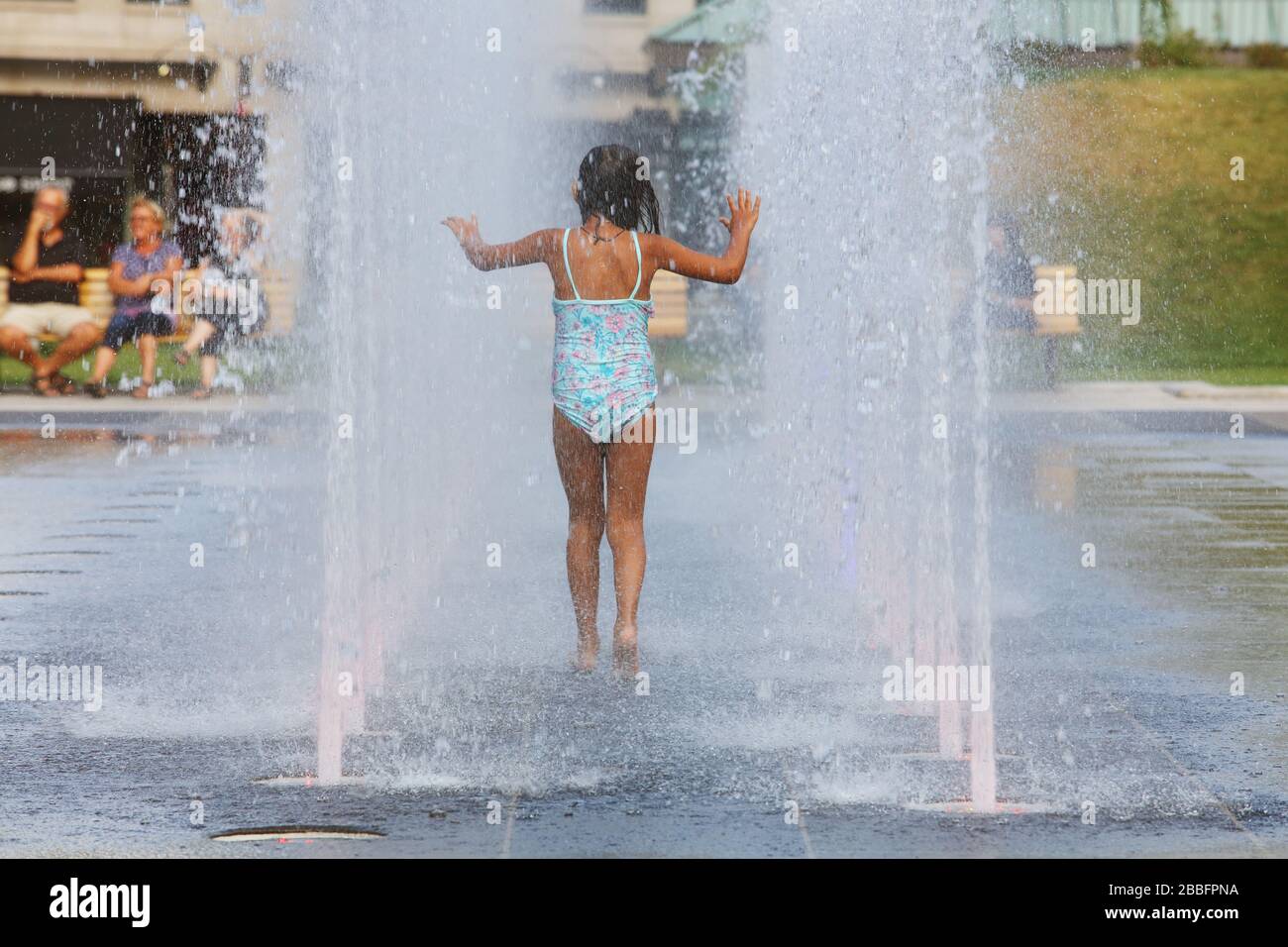 Giovane ragazza che cammina tra due file di fontane d'acqua al Quebec City Hall Gardens, Upper Town, Quebec City, provincia di Quebec, Canada Foto Stock