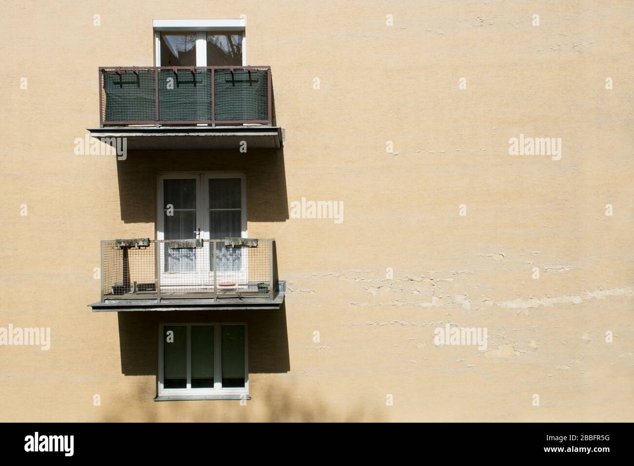 edificio di appartamenti dipinto di giallo con finestre e balcone alla luce del sole Foto Stock