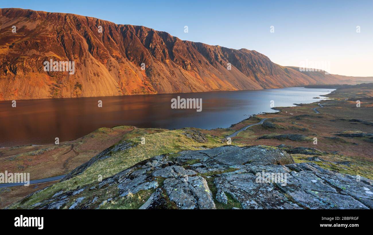 Illgill Head, conosciuto anche come The Screes, si illumina di rosso nell'ultima luce di una giornata primaverile sopra le inky profondità blu di Wast Water, Lake District, UK. Foto Stock