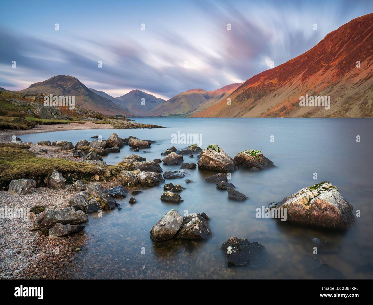 Illgill Head, conosciuto anche come The Screes, si illumina di rosso nell'ultima luce di una giornata primaverile sopra le inky profondità blu di Wast Water, Lake District, UK. Foto Stock