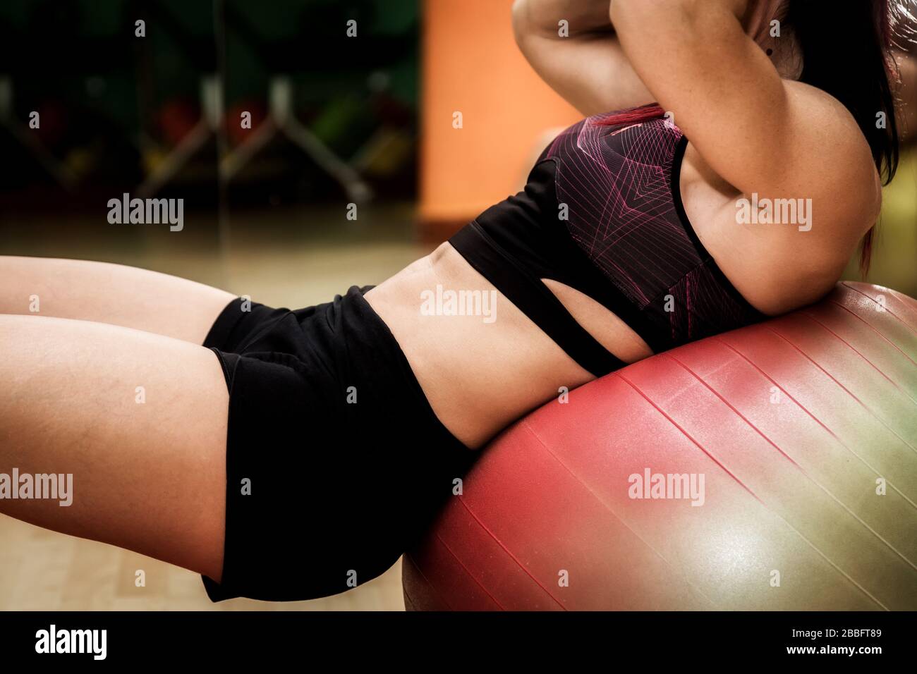 Donna che fa esercizi con fitball in fitness in palestra. Muscoli addominali del nucleo che si impegnano. Concetto di immagine di stile di vita sano per le donne. Foto Stock