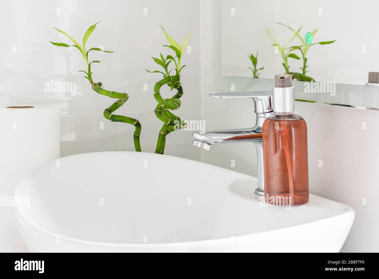 Bottiglia di sapone e rotolo di tovagliolo di carta sul lavello in bianco bagno moderno interno. Concetto di prevenzione delle infezioni batteriche. Foto Stock