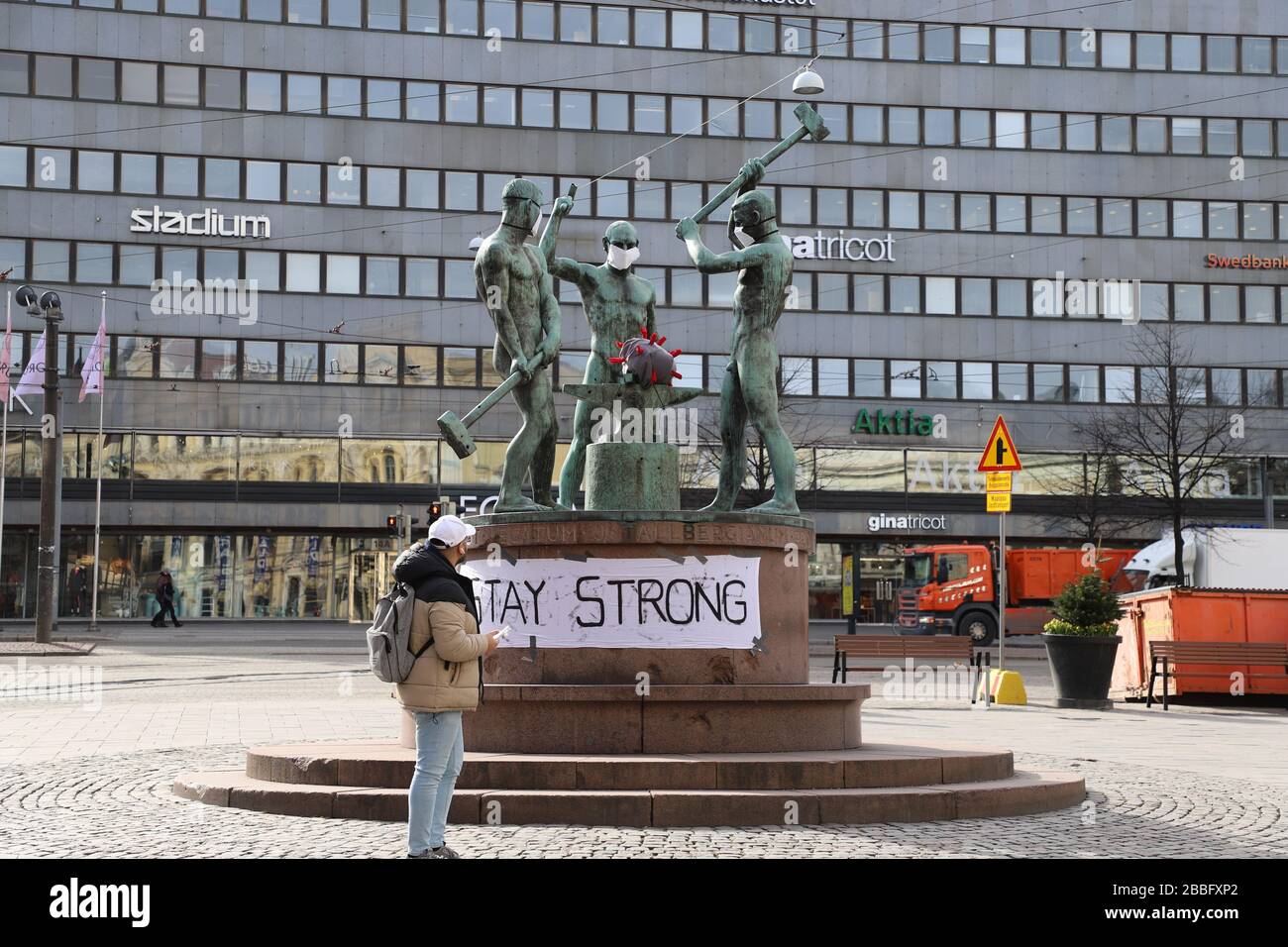 (200331) -- HELSINKI, 31 marzo 2020 (Xinhua) -- un cittadino si ferma alla famosa scultura cittadina 'Three Smiths' che è stata indossata su maschere facciali, a Helsinki, Finlandia, 31 marzo 2020. A partire da lunedì, i casi di coronavirus in Finlandia si attestavano a 1.313 morti, secondo l'Istituto finlandese per la salute e il benessere (THL). (Xinhua/Zhu Haochen) Foto Stock