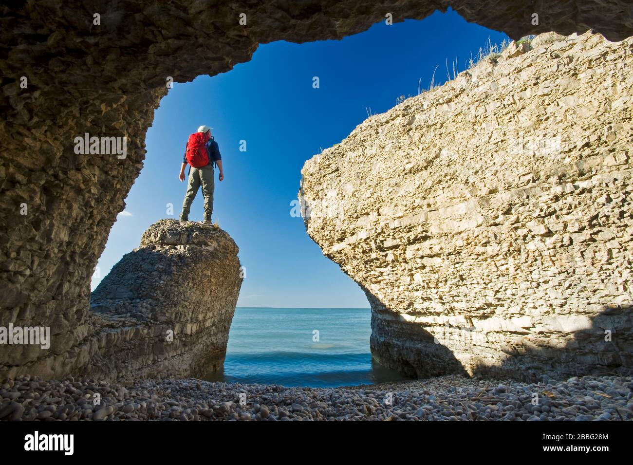 Escursionista lungo scogliere calcaree, roccia ripida, lungo il lago Manitoba, Canada Foto Stock
