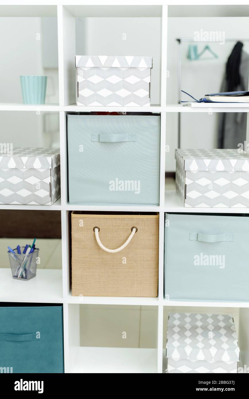 Scatole e organizer in un armadietto bianco per ufficio. Ufficio luminoso in toni blu e beige. Foto Stock