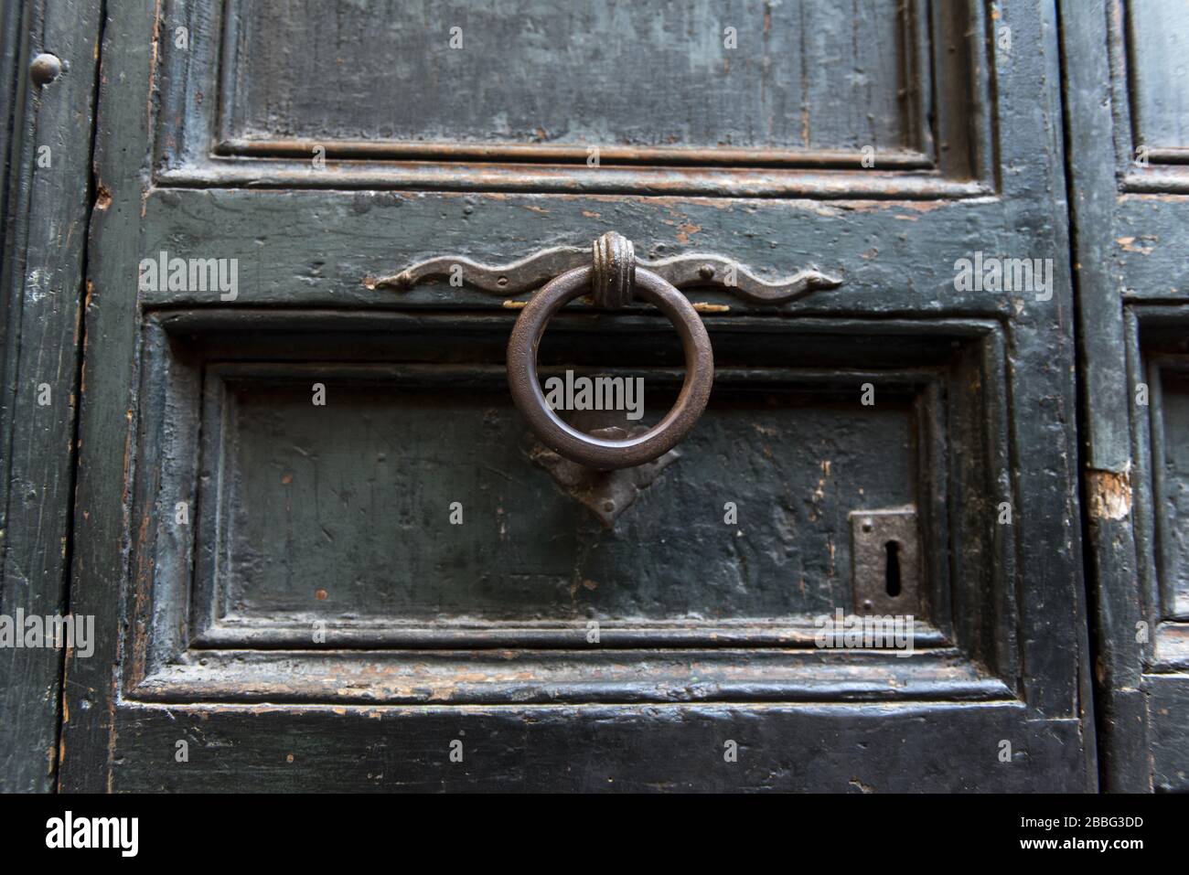 Un vecchio batticalcano metallico su una vecchia porta di legno Foto Stock