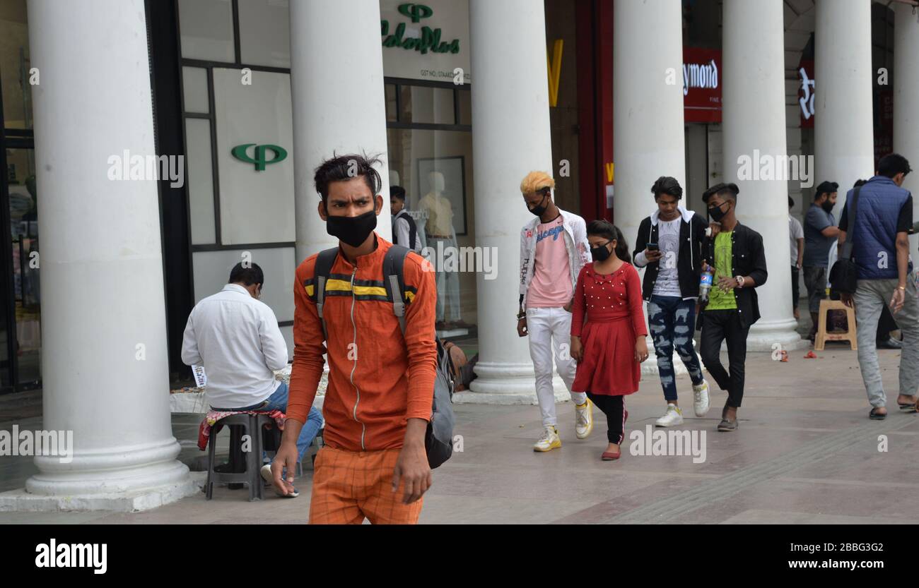 Le persone che indossano maschere facciali camminano nel complesso dello shopping Connaught Place a Nuova Delhi, India. I mercati sono in gran parte deserti con i negozi chiusi come le persone sono s. Foto Stock