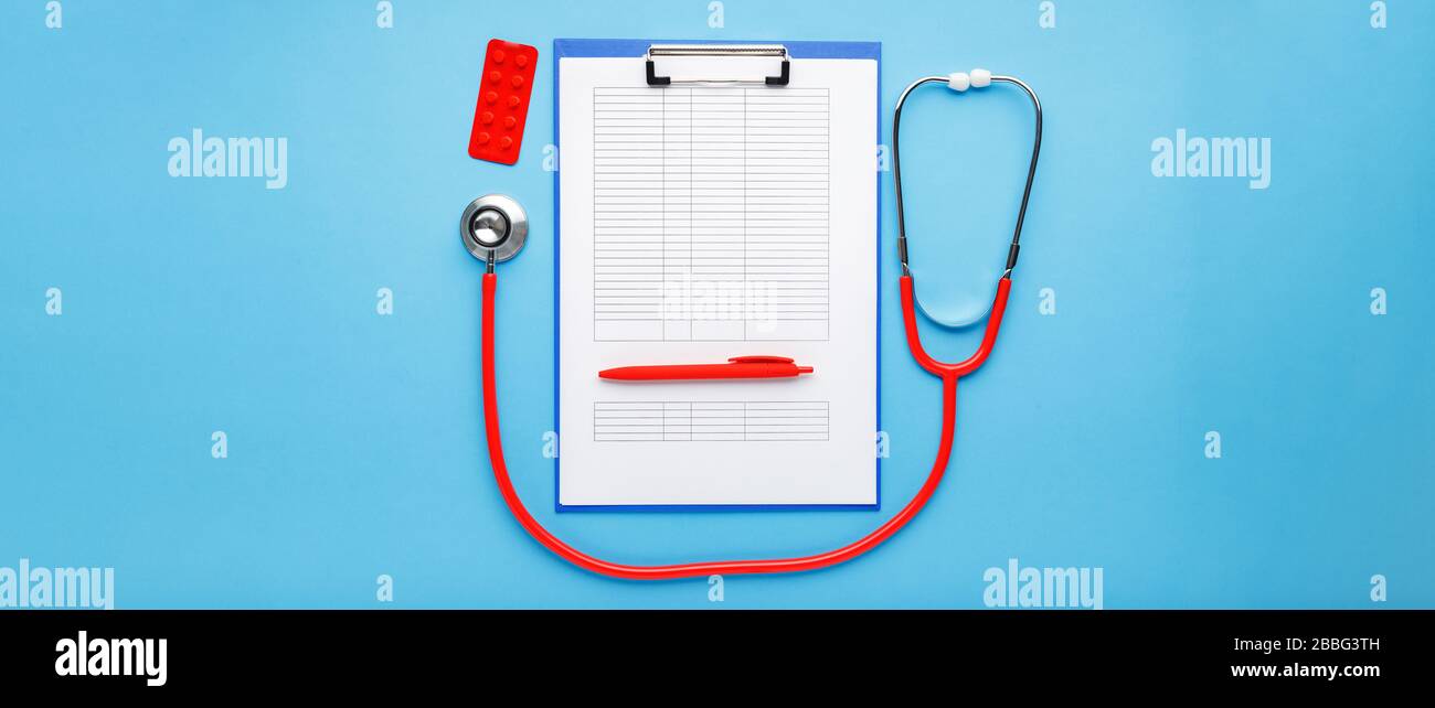 Appuntamento medico. Stetoscopio rosso, compresse, documenti medici sul posto di lavoro dei medici in clinica lungo banner blu. Concetto di medicina sanitaria Foto Stock
