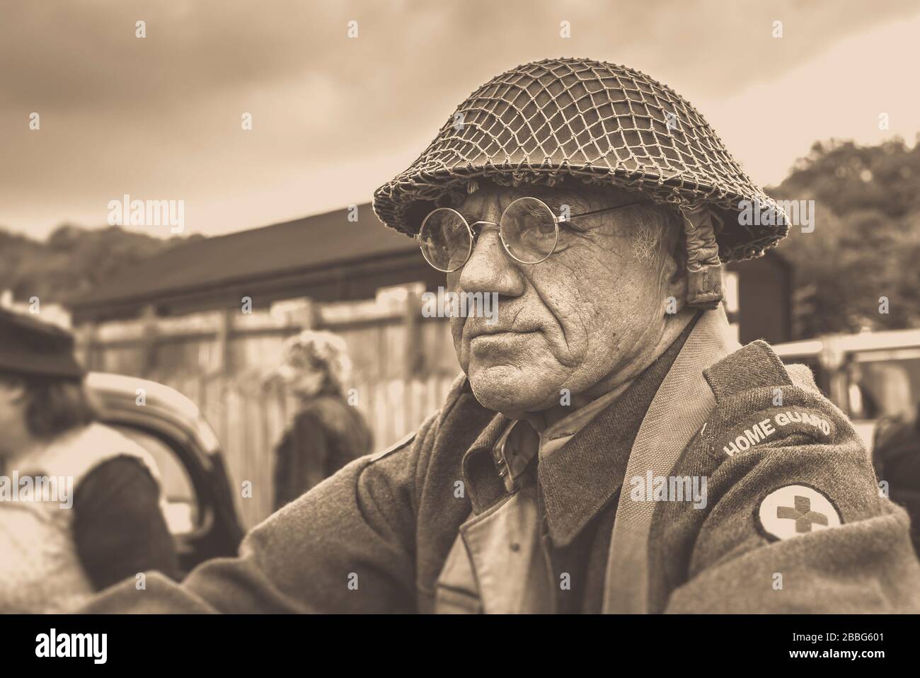 Moody, seppia primo piano di uomo anziano in casco vestito in costume anni '40 come Home Guard Army Medic, evento estivo anni '40, Black Country Museum, Dudley, Regno Unito. Foto Stock