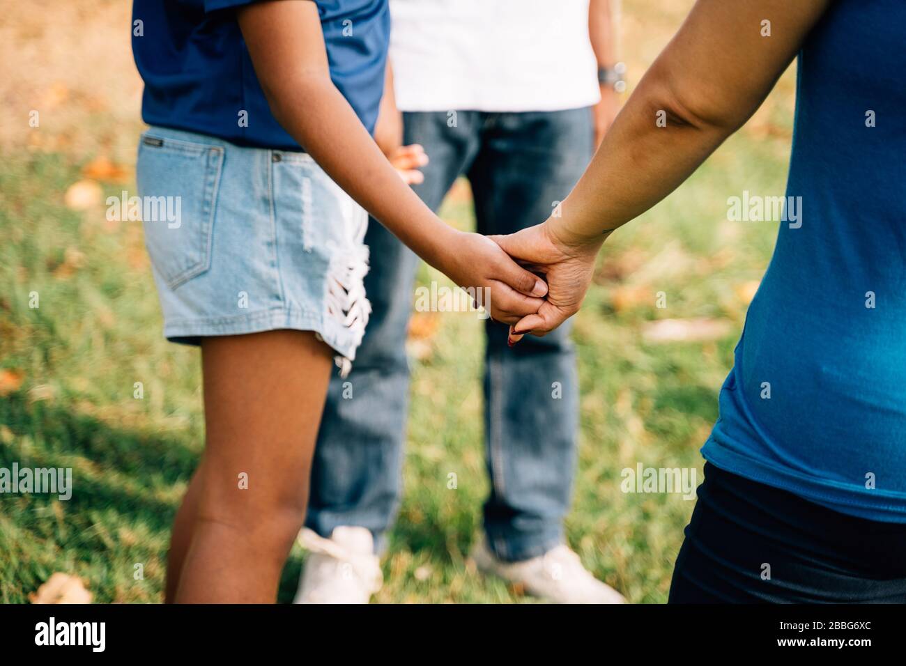 Famiglia speranzosa di padre e di figlia, e madre che tiene le mani insieme in cerchio nel parco. Preghiera di Gesù Cristo cattolico e concetto di ringraziamento Foto Stock