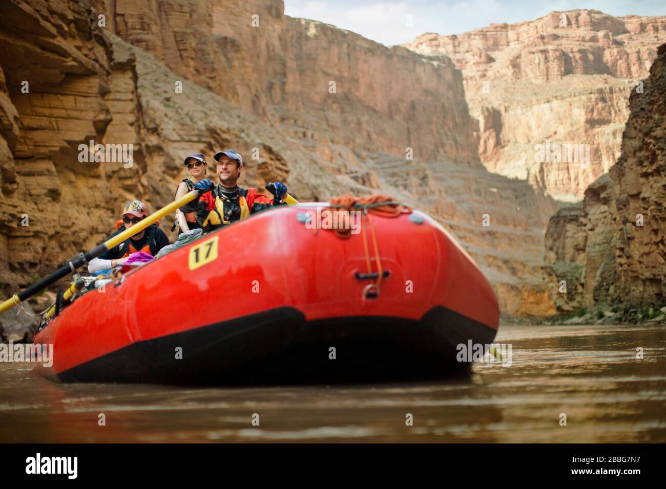 Gruppo sorridente di amici divertendosi mentre rafting insieme sulle rive di un fiume in un canyon rocciosi. Foto Stock
