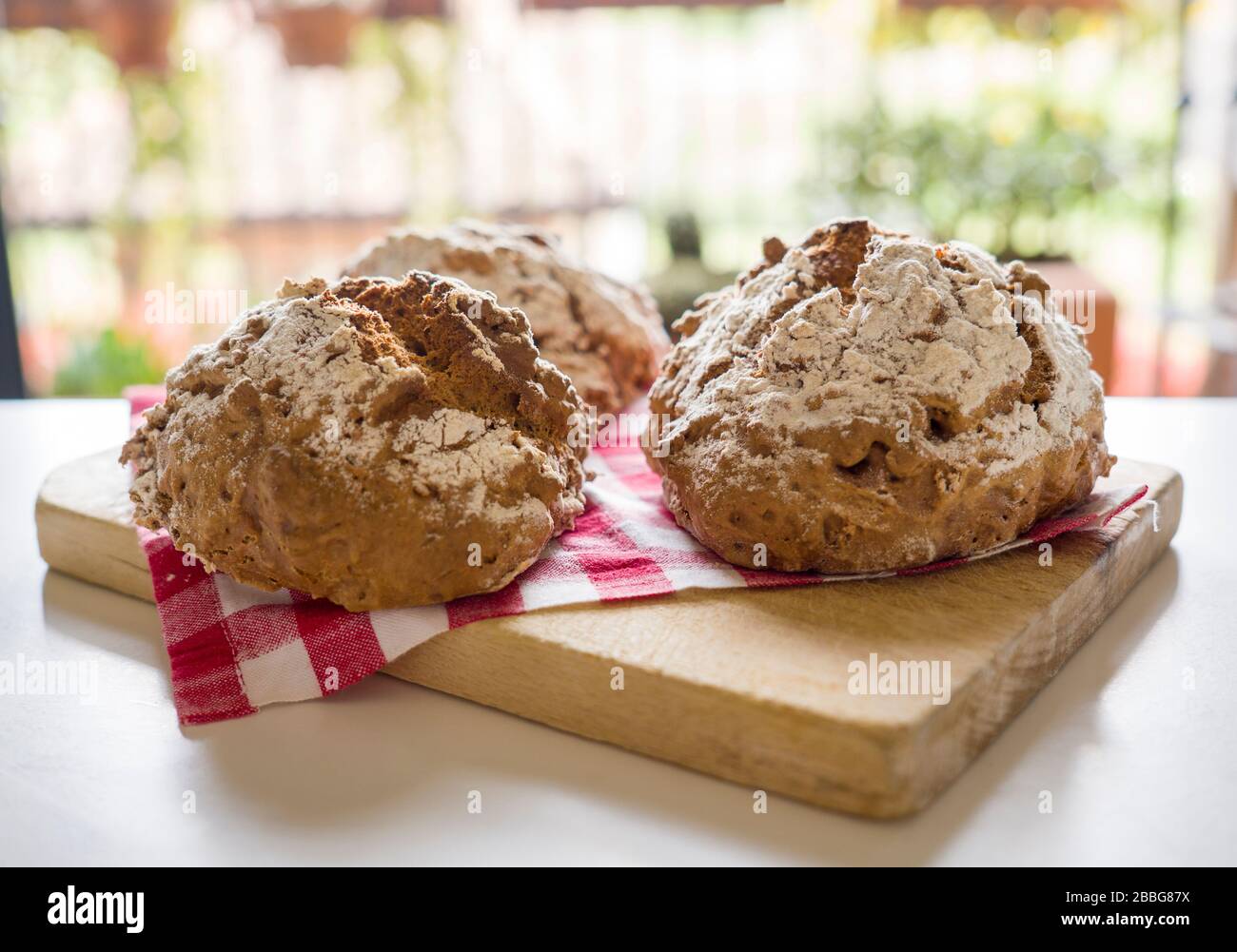 Pane fatto in casa su tagliere con tovagliolo rosso e bianco a scacchi. Foto Stock