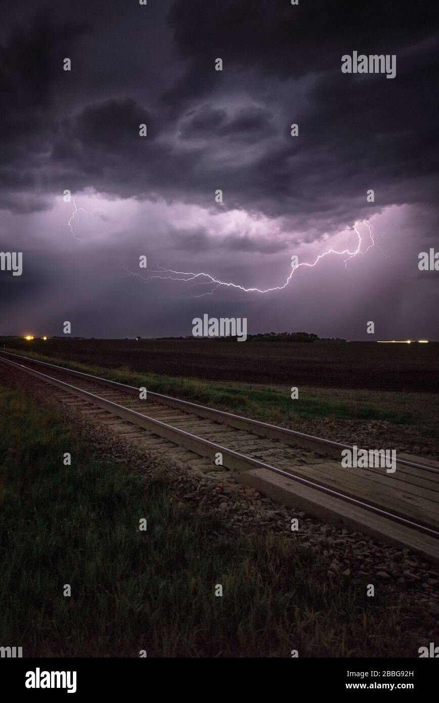Tempesta con fulmini lampeggiante ferrovia di attraversamento e binari del treno nel sud di Manitoba Canada Foto Stock