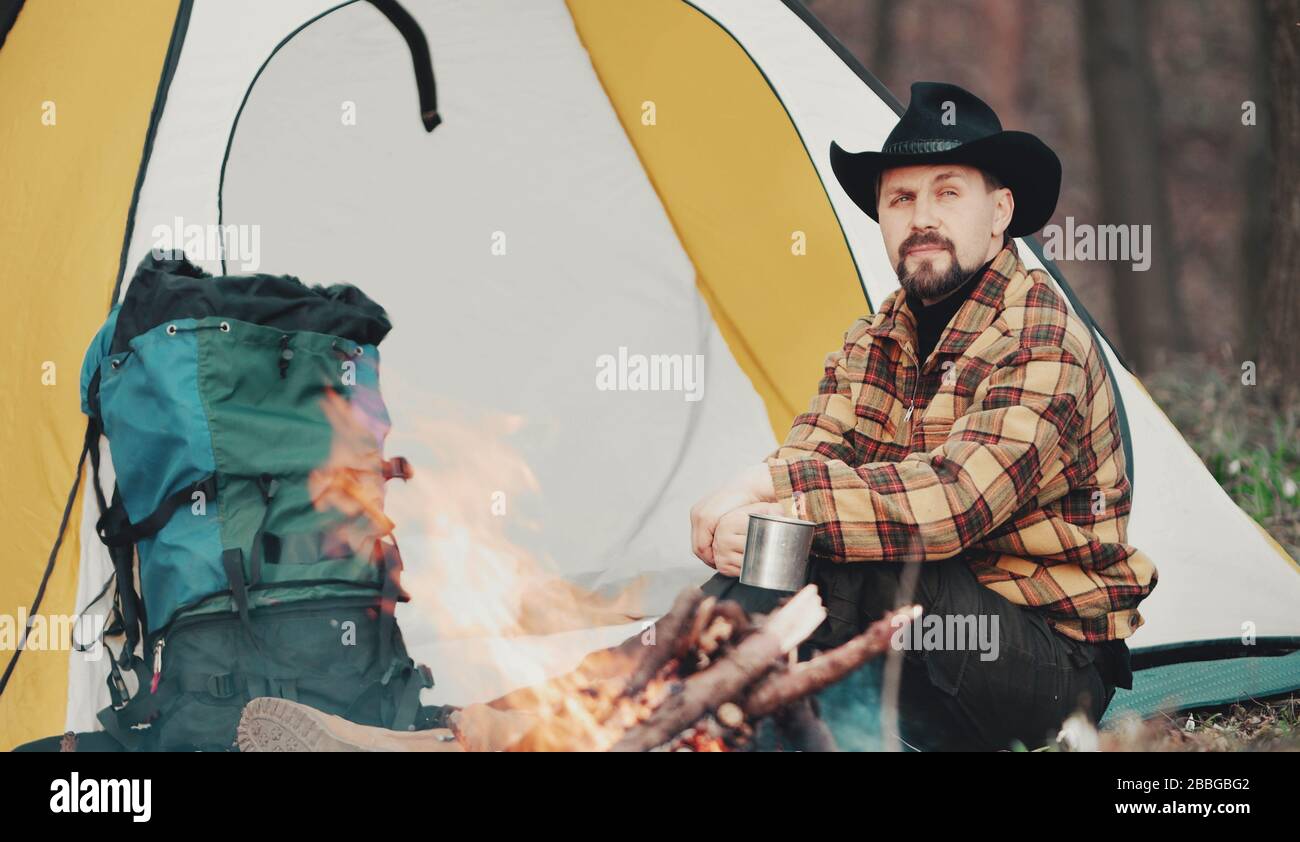Uomo che ha tè al fuoco campfire Foto Stock
