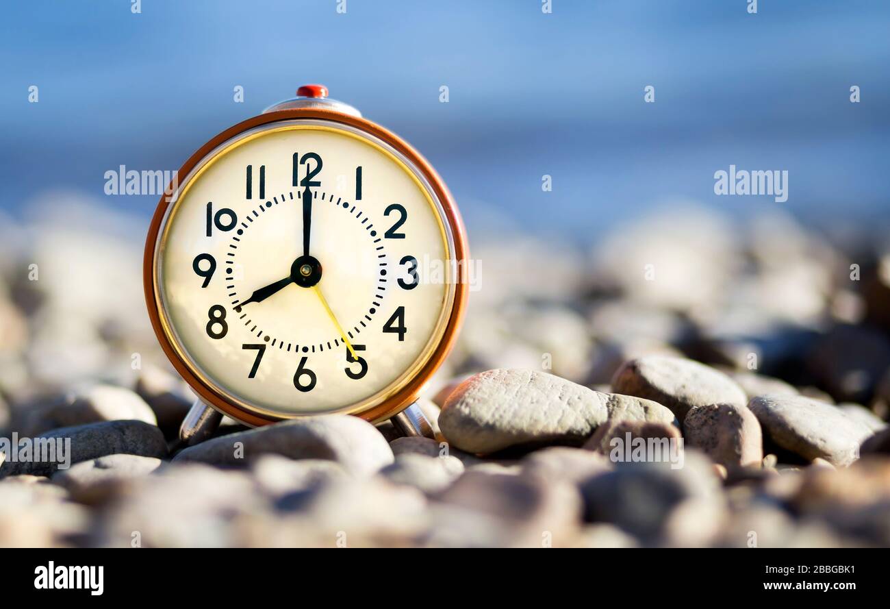 Concetto di ora legale, sveglia retro in piedi sulla spiaggia Foto Stock