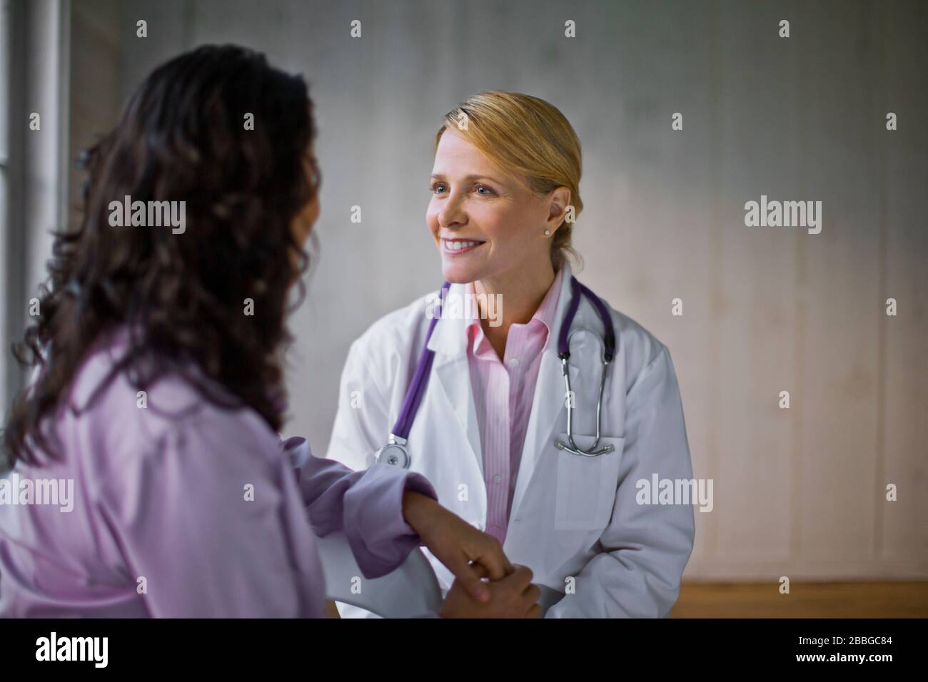 Medico di sesso femminile medio adulto che parla con un paziente Foto Stock